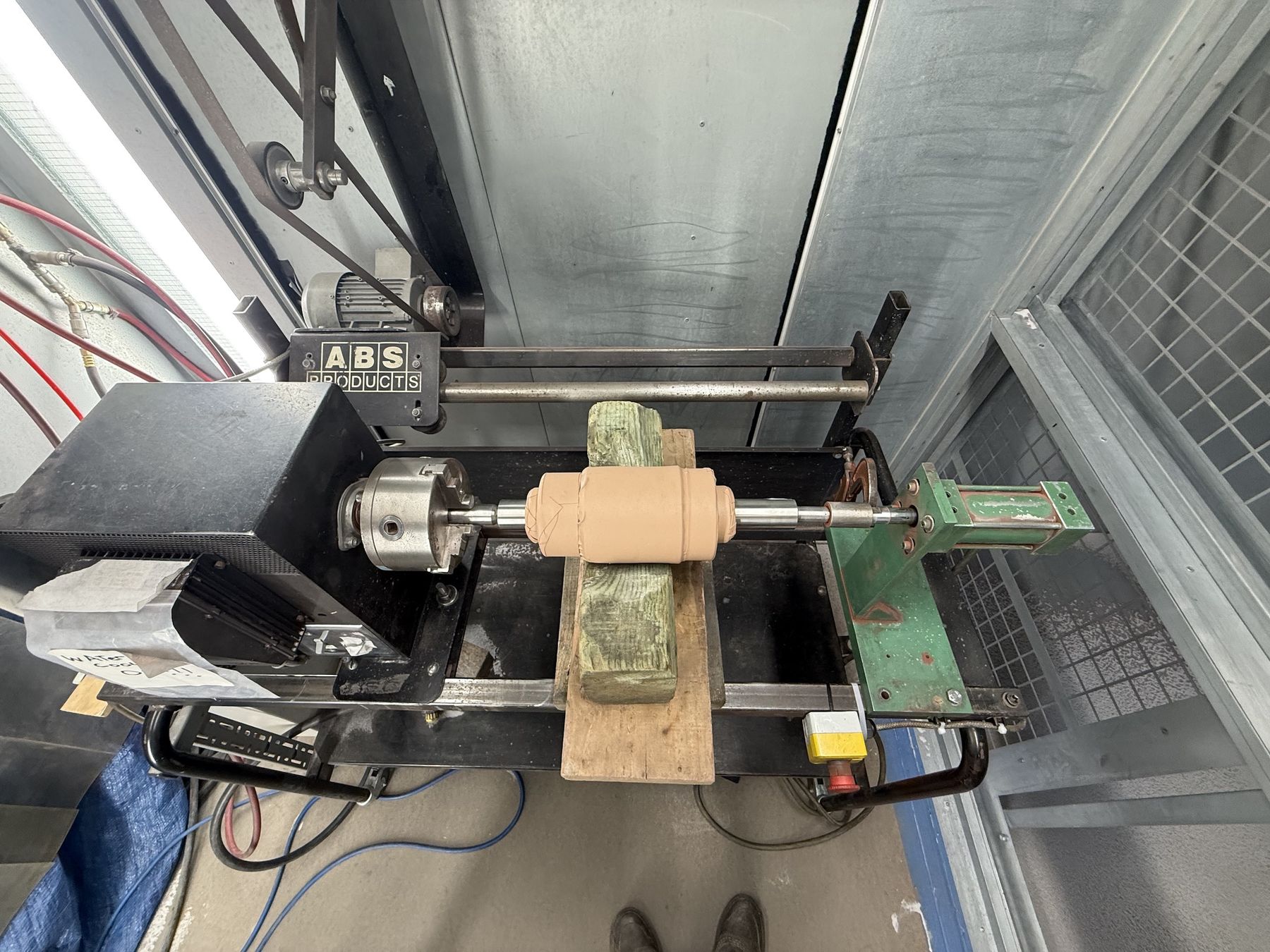 Forming roller shaft mounted on rotary jig inside cold spray booth