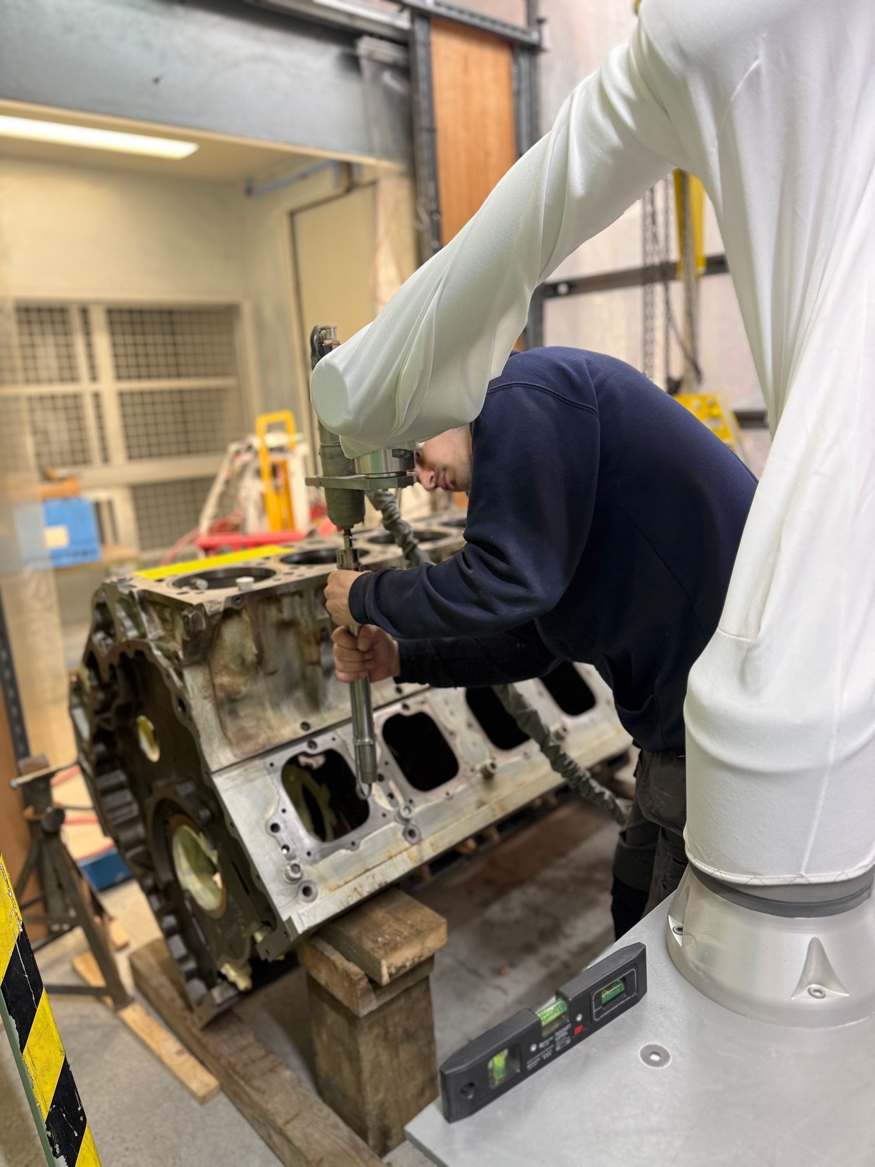 Cold spray robot arm applying nickel coating to V12 engine block