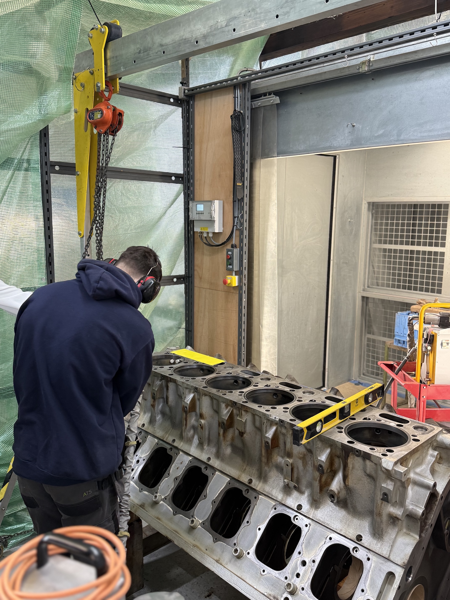 Technician levelling a large V12 engine block before cold spray liner bore repair